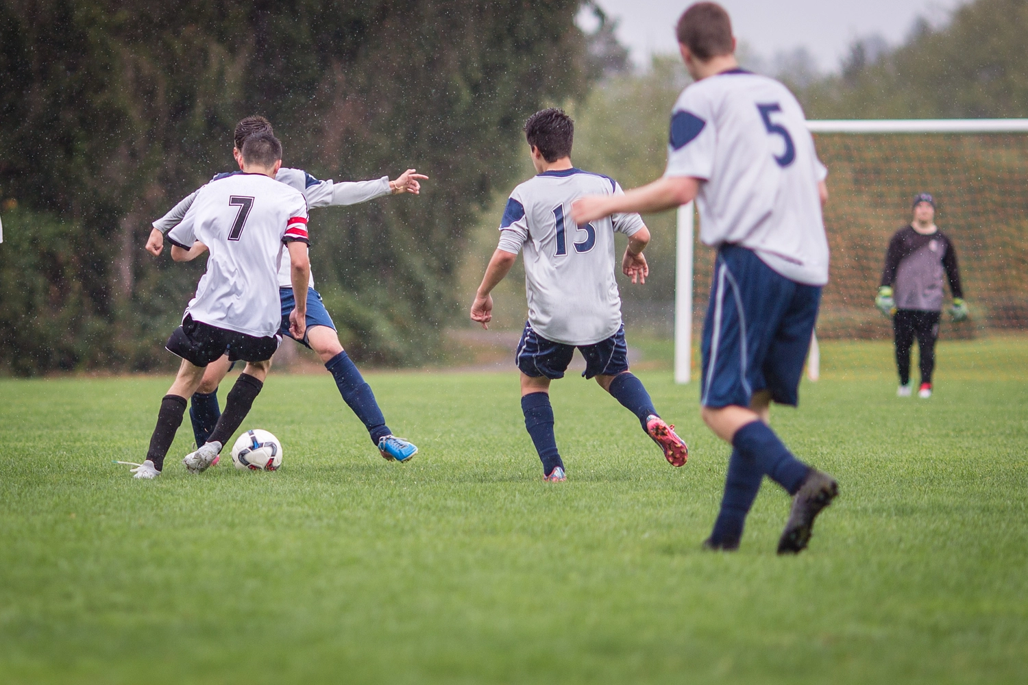 FC Friedrichstadt - Fußballverein - Junge Männer spielen im Regen auf einem Rasenplatz Fußball